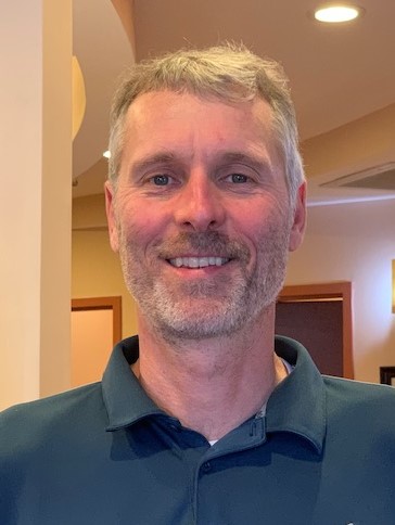 Close-up portrait of Asheville, NC chiropractor and acupuncturist Dr. Bart Hodgins smiling in a blue polo shirt.